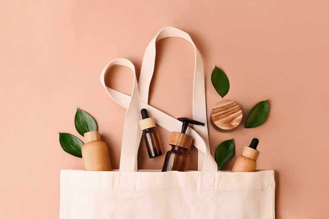 Eko kozmeticki proizvodi sa platnenom torbom i listovima biljke.