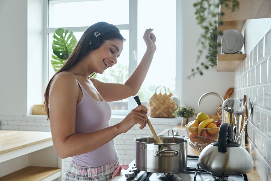 Žena sluša muziku dok kuva u čistoj kuhinji