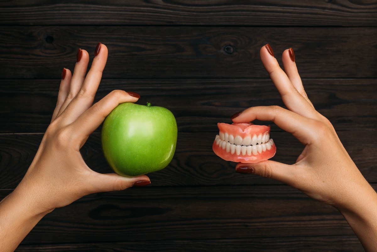 zena-drzi-jabuku-i-zubne-implante