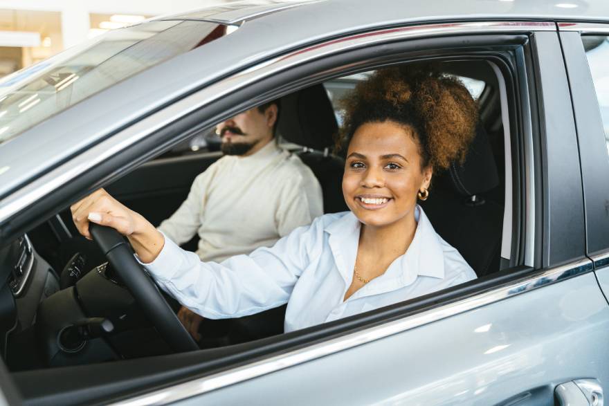 nasmejana žena vozi automobil sa muškarcem